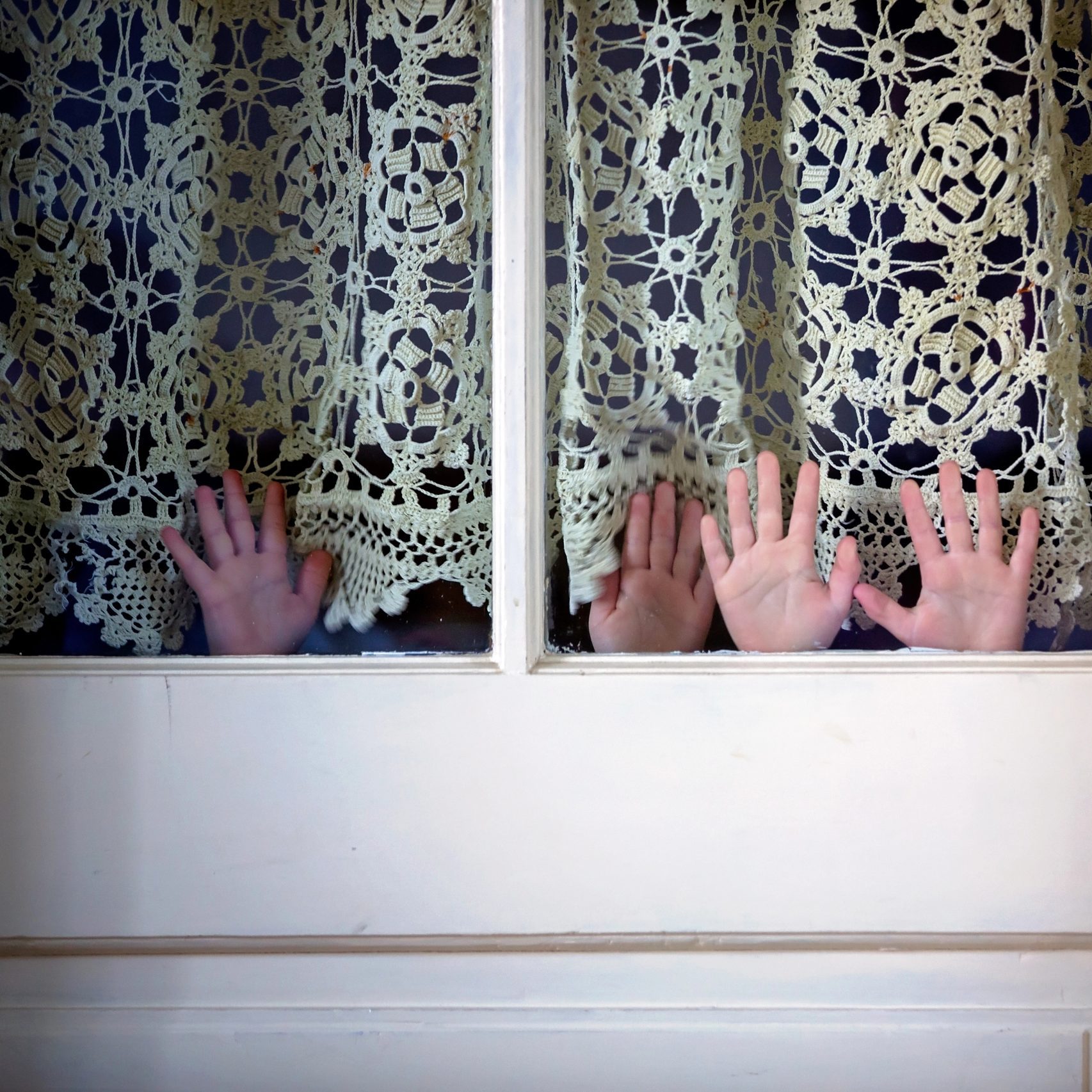 Children's hands playfully  held up in a doorway