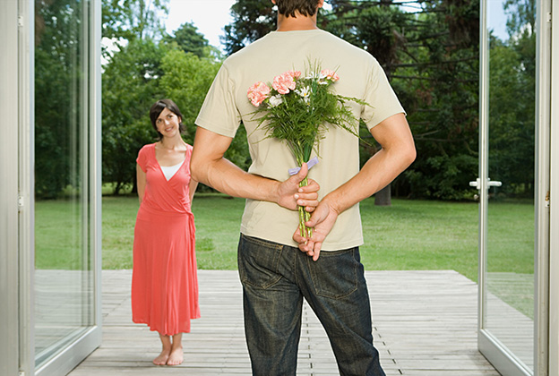 A man holding flowers while his date walks through doors