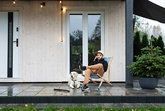 A man sitting with his dog in front of the doors of his house