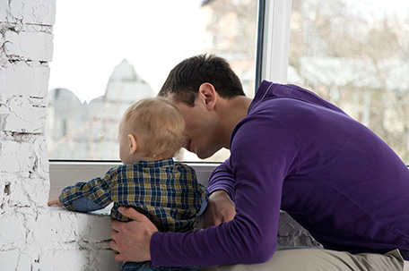 A man and his young son looking out through a window