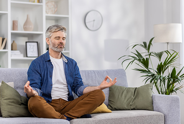 A man meditating in the light from his windows